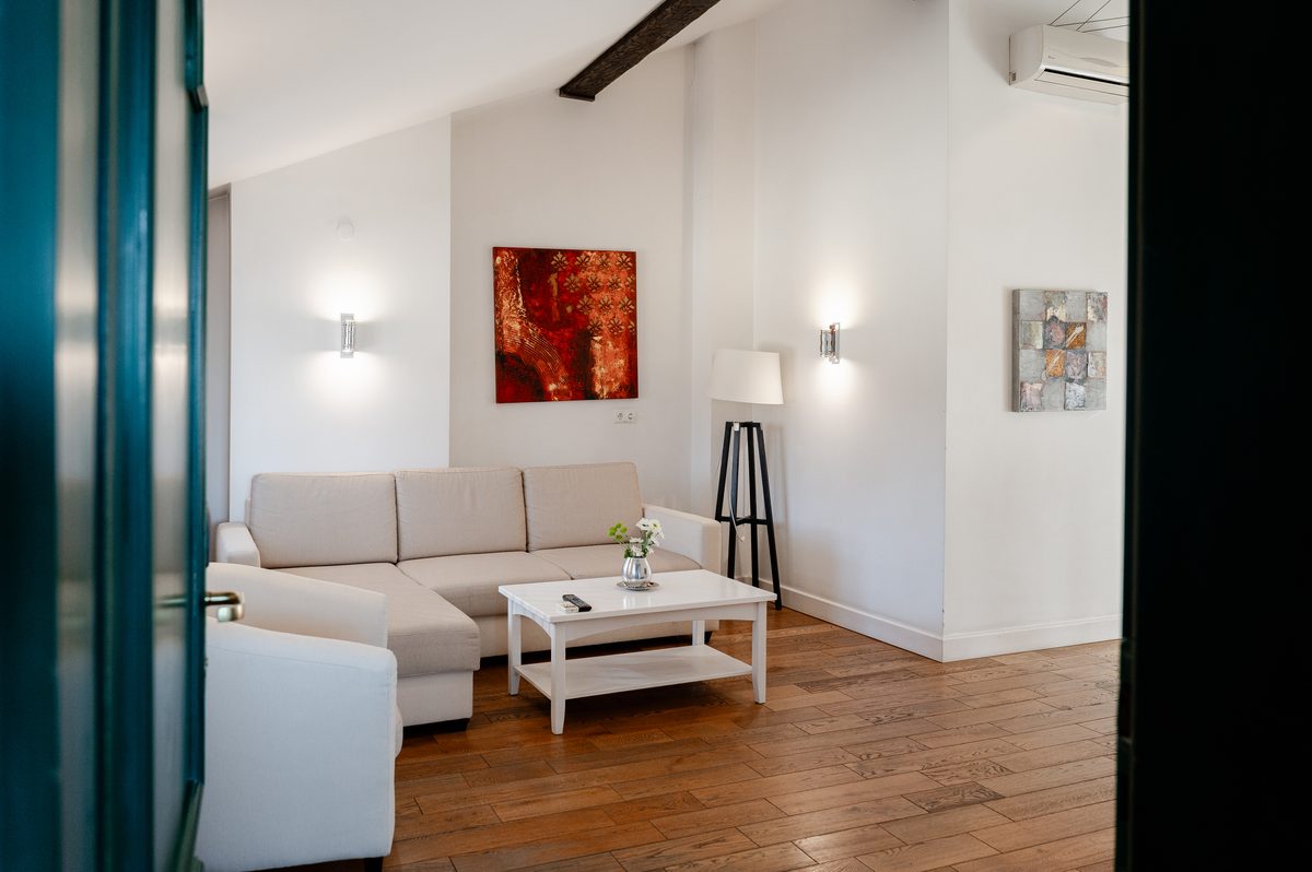 Das Wohnzimmer: ein Ecksofa, ein weißer Couchtisch und ein rotes Gemälde