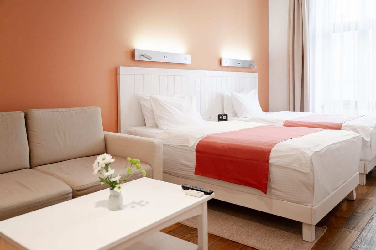 Standardzimmer: zwei Einzelbetten, ein Sofa und ein niedriger Tisch mit Blumen