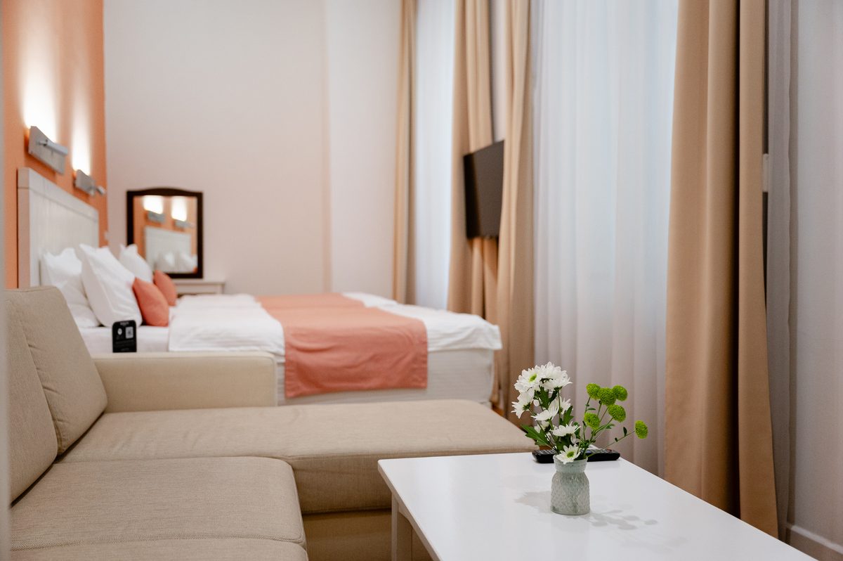 Junior Suite: sofa i niski stolik z kwiatami, w głębi łóżka
