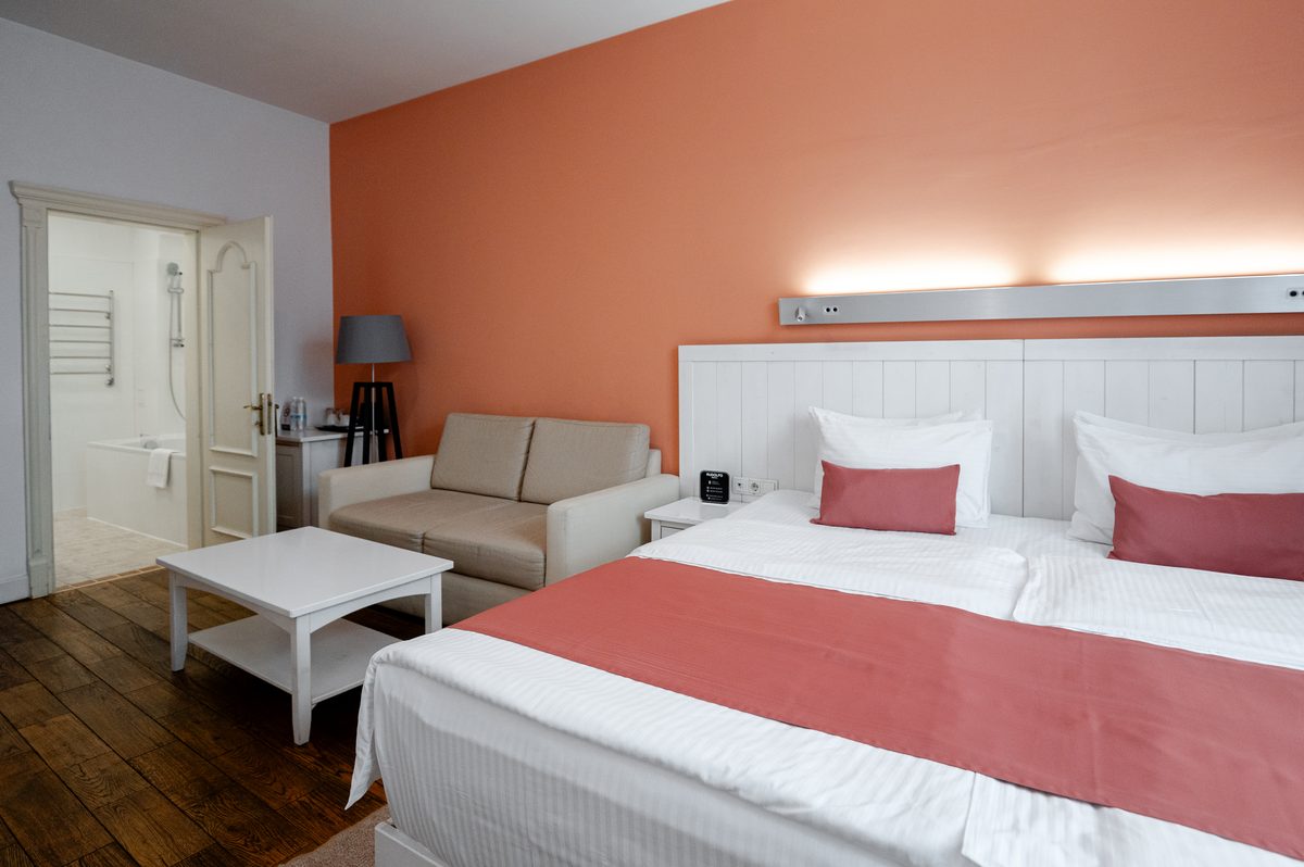 Standardzimmer: die Betten, ein kleines Sofa und die offene Tür zum Bad
