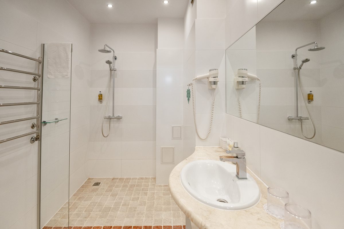 Bad: Dusche hinter einer Glaswand, ein Handtuchhalter, Waschbecken und Haartrockner